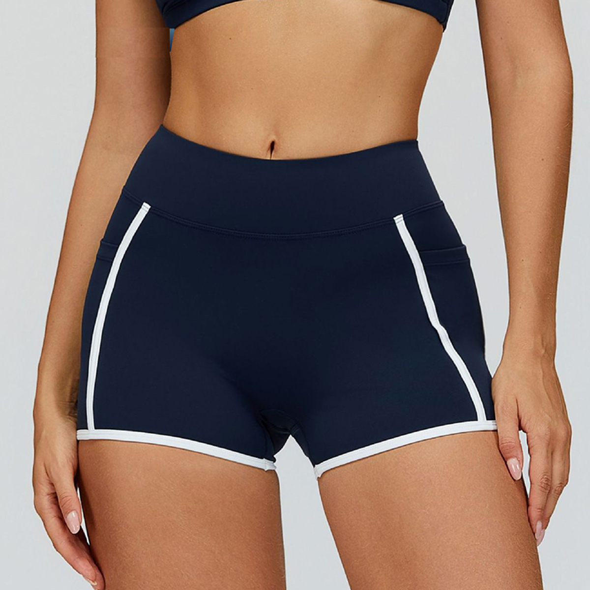 Navy blue athletic shorts with white trim worn by a person on a light gray background