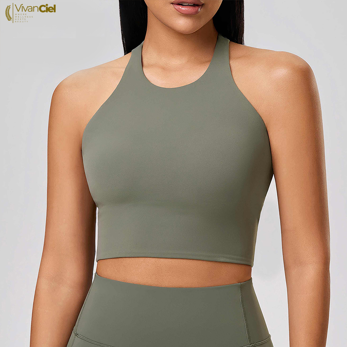 Woman wearing a green sports bra and leggings with a plain background